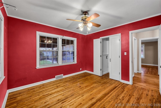 unfurnished bedroom with ceiling fan, wood-type flooring, and crown molding