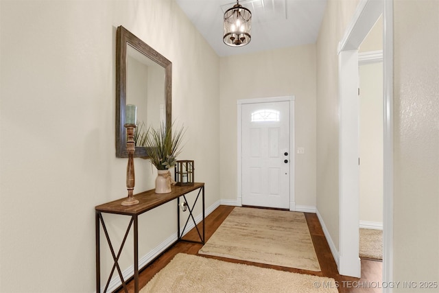 foyer featuring dark wood-type flooring and a chandelier