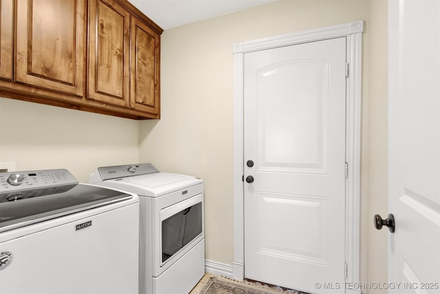 clothes washing area featuring cabinets and washer and clothes dryer