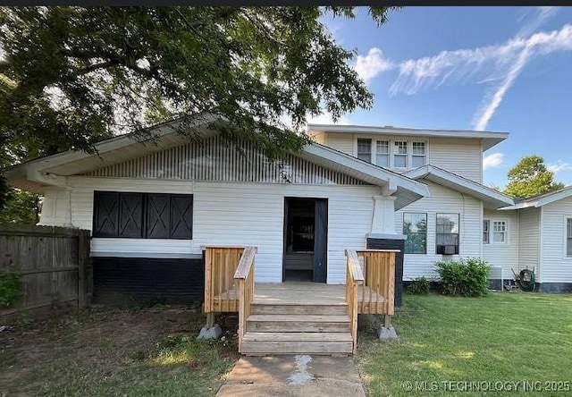 rear view of property with fence, a deck, and a lawn