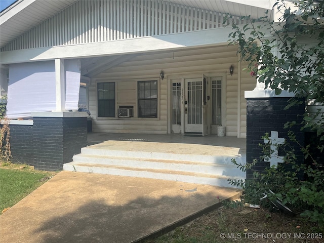 entrance to property featuring covered porch and cooling unit