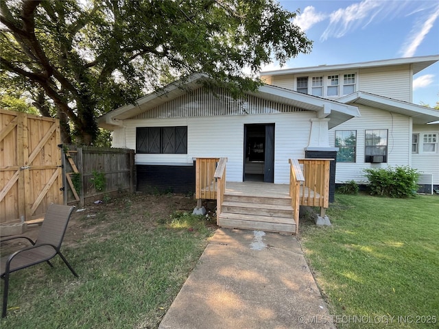 rear view of house featuring a lawn, a gate, fence, a deck, and a garage