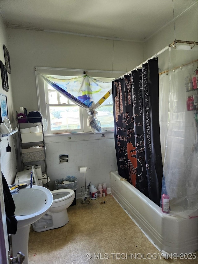 bathroom with tile walls, toilet, and shower / bath combo with shower curtain