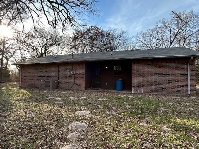 back of property featuring central AC and brick siding