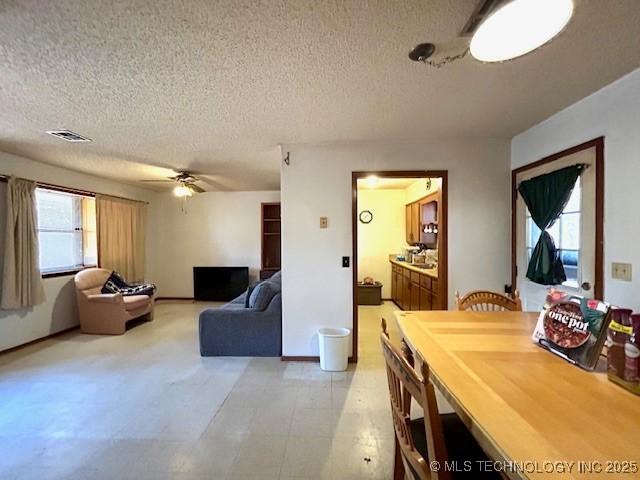 living area featuring a ceiling fan, visible vents, and a textured ceiling