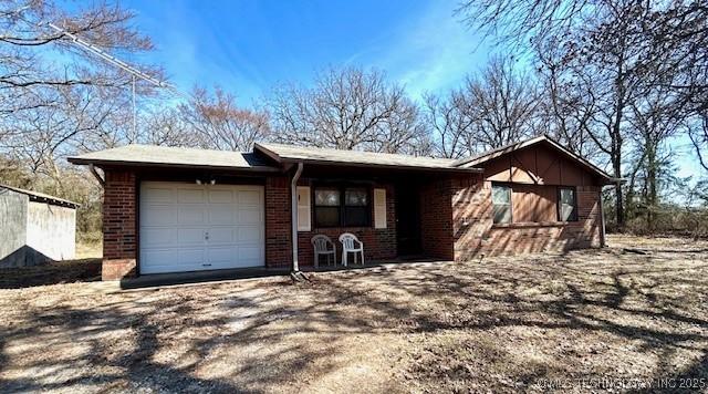 view of front of house with a garage, brick siding, and dirt driveway