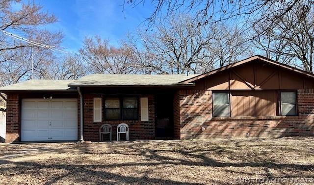 single story home with dirt driveway, brick siding, and a garage