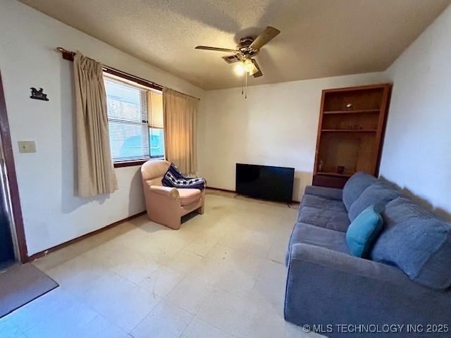 living room featuring light floors, ceiling fan, and a textured ceiling