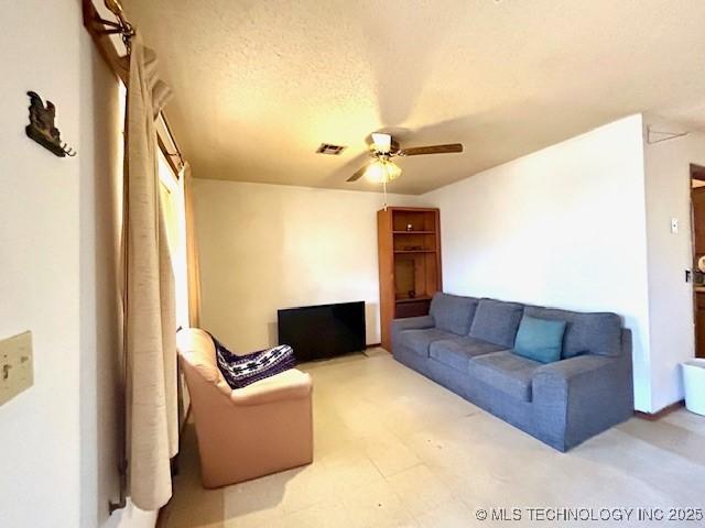 living room featuring visible vents, ceiling fan, and a textured ceiling