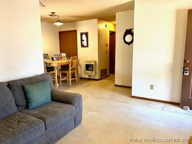 living room featuring baseboards, light floors, visible vents, and heating unit