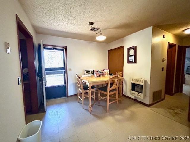 dining room with visible vents, a textured ceiling, and heating unit