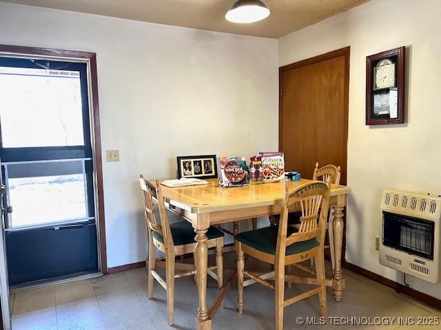 dining space with baseboards, a healthy amount of sunlight, and heating unit