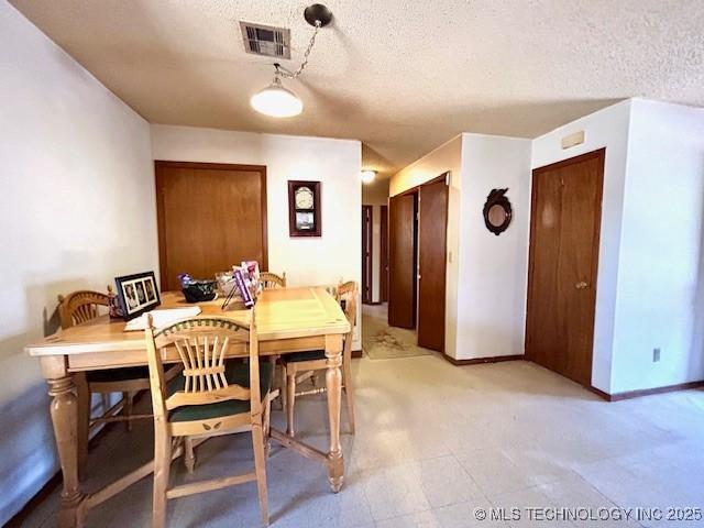 dining space featuring baseboards, visible vents, and a textured ceiling