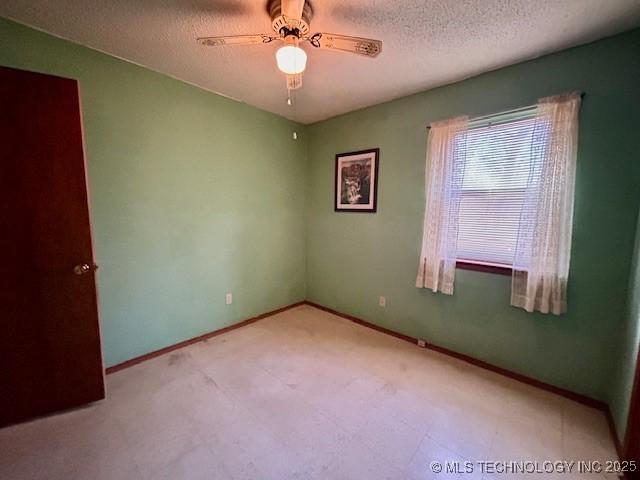 unfurnished room featuring a textured ceiling, a ceiling fan, and baseboards