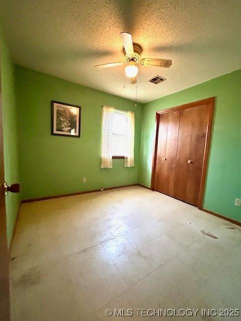 unfurnished bedroom featuring baseboards, visible vents, a textured ceiling, light floors, and a closet