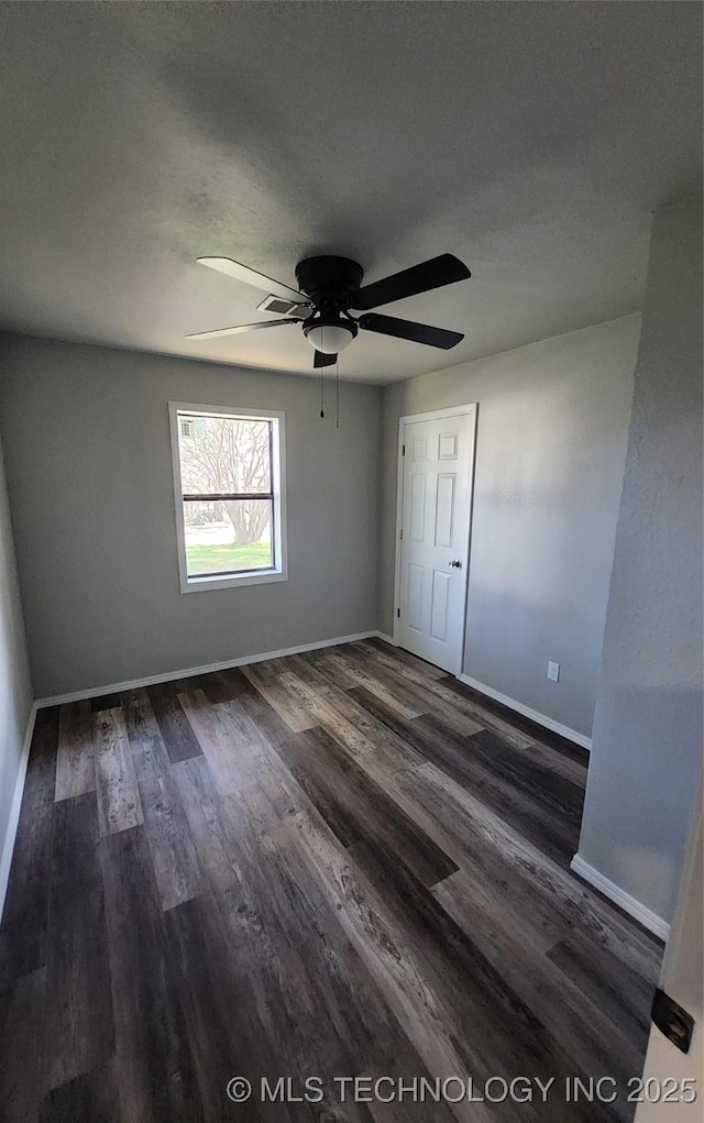 empty room with ceiling fan, dark wood-type flooring, and a textured ceiling