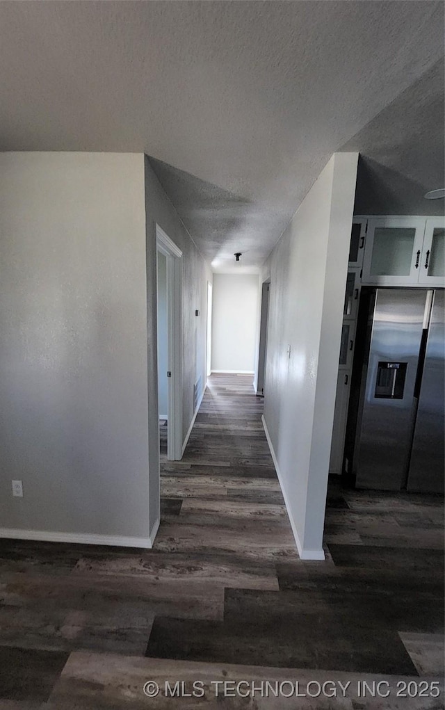 hall with a textured ceiling and dark wood-type flooring