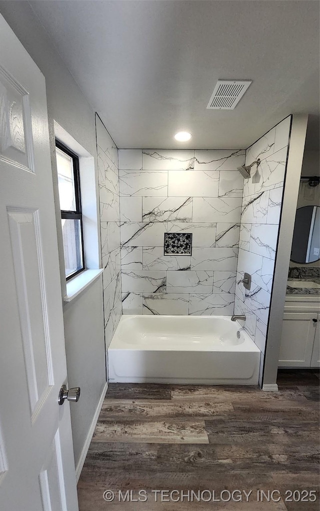 bathroom featuring hardwood / wood-style floors, vanity, and tiled shower / bath