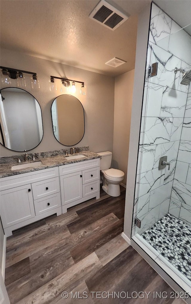 bathroom featuring vanity, a shower with door, hardwood / wood-style flooring, toilet, and a textured ceiling