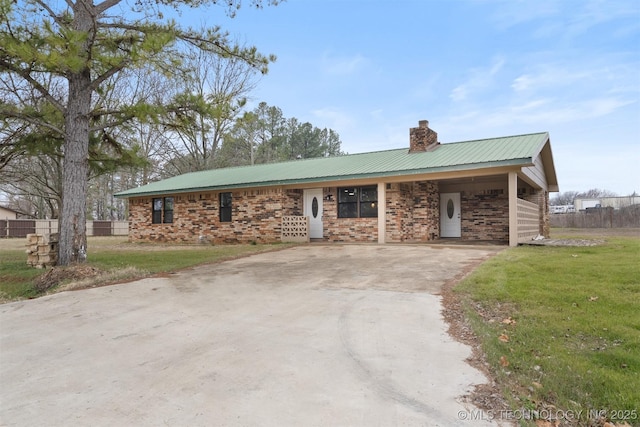 single story home with brick siding, a chimney, metal roof, driveway, and a front lawn