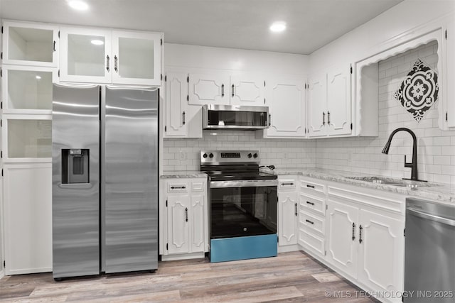 kitchen with stainless steel appliances, light wood-type flooring, a sink, and white cabinets