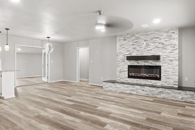 unfurnished living room with light wood-style floors, a fireplace, and baseboards