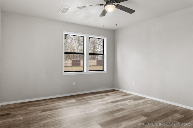 unfurnished room featuring a ceiling fan, wood finished floors, visible vents, and baseboards