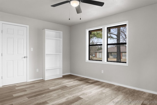 unfurnished bedroom with a ceiling fan, light wood-style flooring, and baseboards