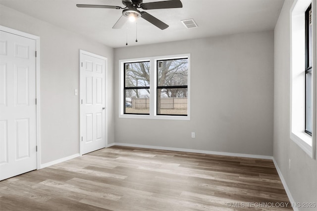 interior space featuring light wood finished floors, baseboards, visible vents, and a ceiling fan