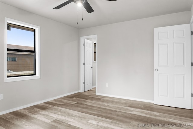 empty room with ceiling fan, baseboards, and wood finished floors