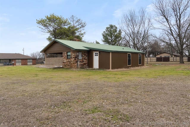 exterior space featuring brick siding, metal roof, and a lawn