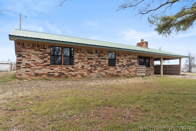 view of property exterior with brick siding, a yard, a chimney, metal roof, and an attached carport