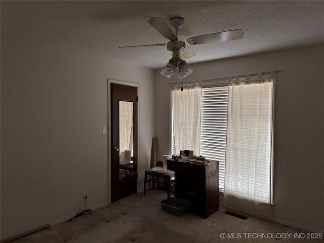 interior space featuring ceiling fan, a textured ceiling, carpet floors, and a healthy amount of sunlight