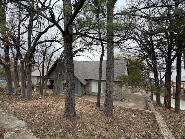 view of property exterior with stone siding and a shingled roof