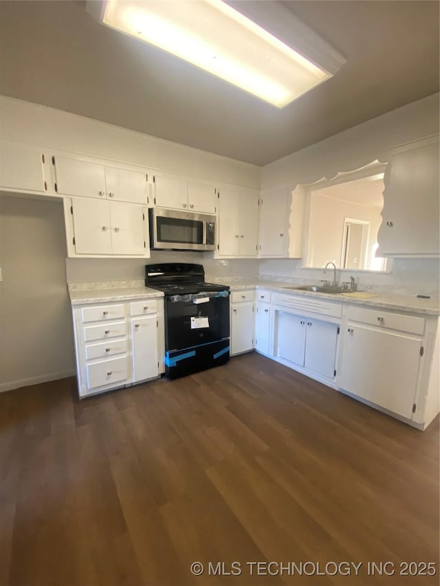 kitchen with black range oven, sink, white cabinets, and dark wood-type flooring