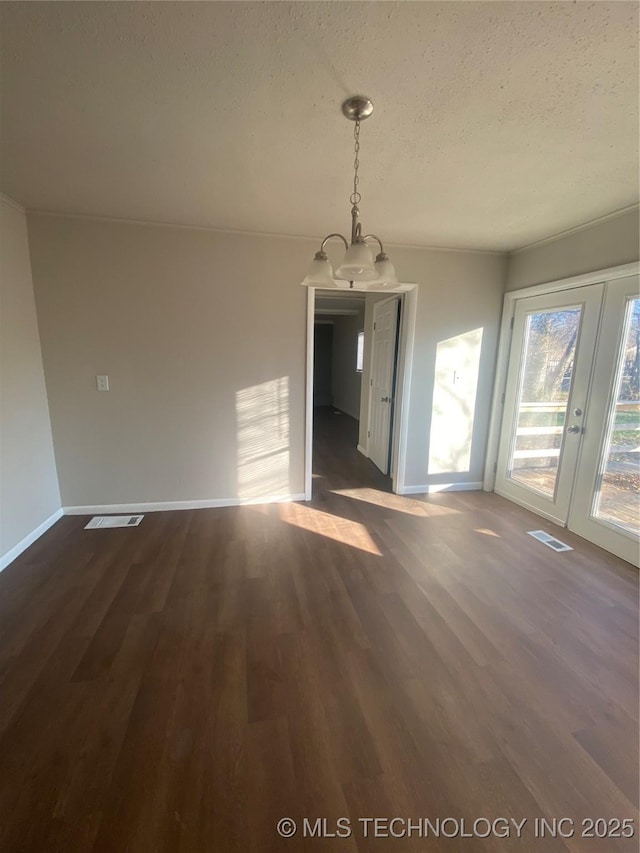 unfurnished dining area featuring dark wood-type flooring, a textured ceiling, and an inviting chandelier