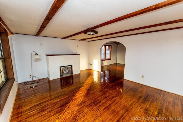 unfurnished living room with beam ceiling, a fireplace, a textured ceiling, and hardwood / wood-style flooring