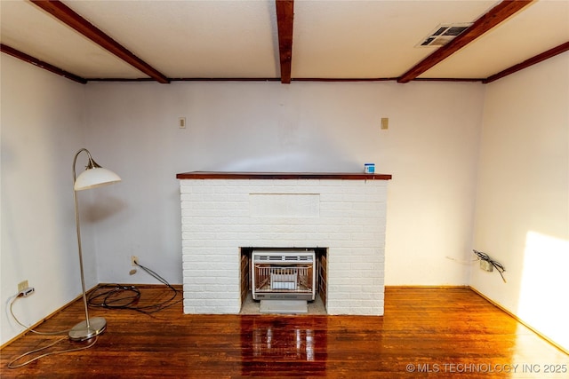 details featuring beamed ceiling, hardwood / wood-style floors, heating unit, and a brick fireplace