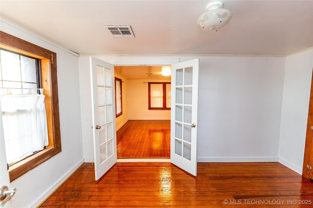 empty room featuring french doors, ornamental molding, and wood-type flooring