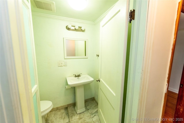 bathroom featuring toilet, crown molding, and sink