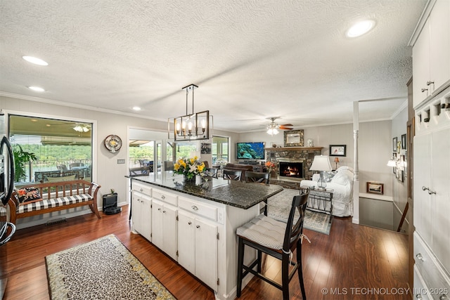 kitchen with white cabinetry, crown molding, a kitchen bar, a fireplace, and a kitchen island