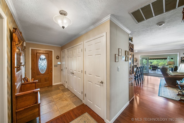 entryway with crown molding, hardwood / wood-style floors, and a textured ceiling