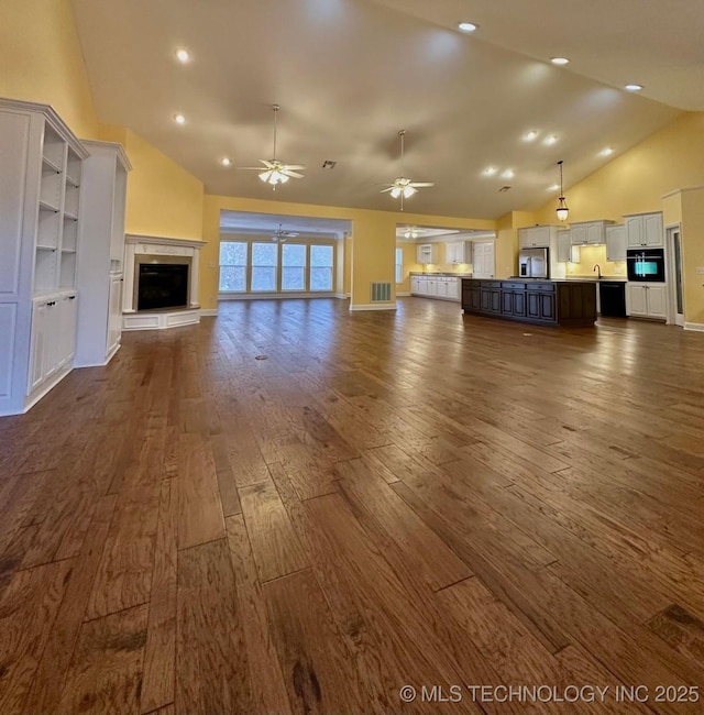 unfurnished living room with ceiling fan, a fireplace, high vaulted ceiling, and dark wood-type flooring