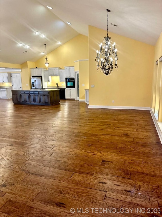 unfurnished living room with dark hardwood / wood-style flooring, high vaulted ceiling, a notable chandelier, and sink