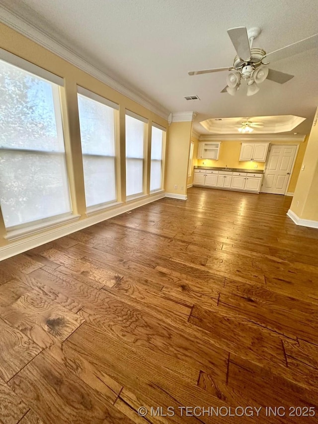 unfurnished living room with hardwood / wood-style floors, ceiling fan, and ornamental molding