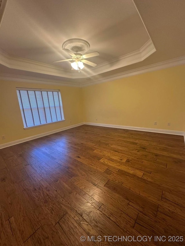 spare room with ceiling fan, a raised ceiling, ornamental molding, and dark wood-type flooring