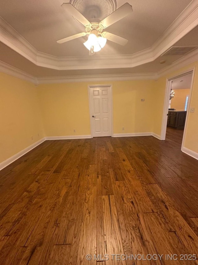 empty room with a tray ceiling, ceiling fan, dark hardwood / wood-style flooring, and ornamental molding