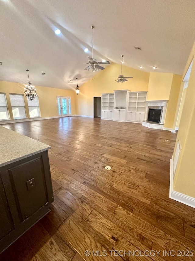 unfurnished living room featuring dark hardwood / wood-style flooring, lofted ceiling with beams, and ceiling fan with notable chandelier