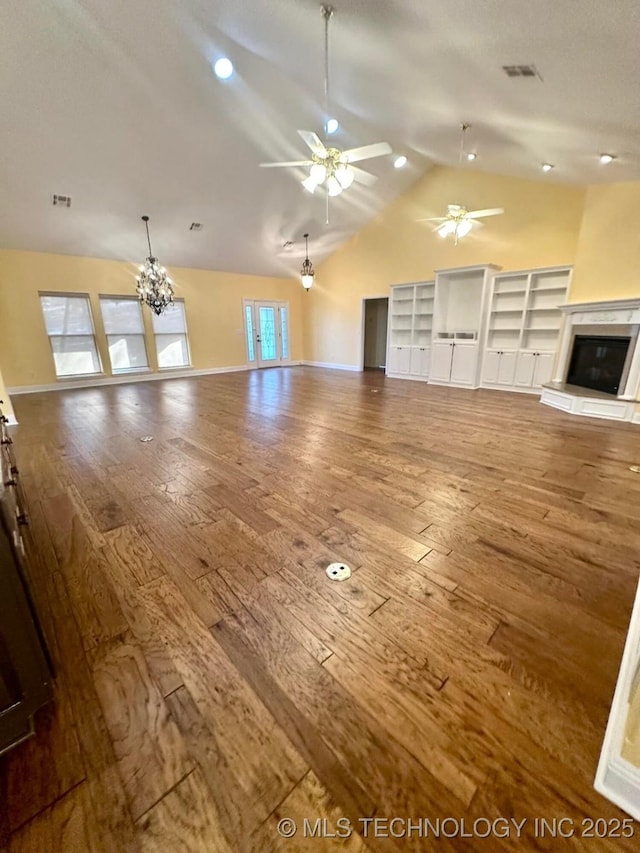 unfurnished living room featuring hardwood / wood-style floors, ceiling fan with notable chandelier, a large fireplace, and lofted ceiling