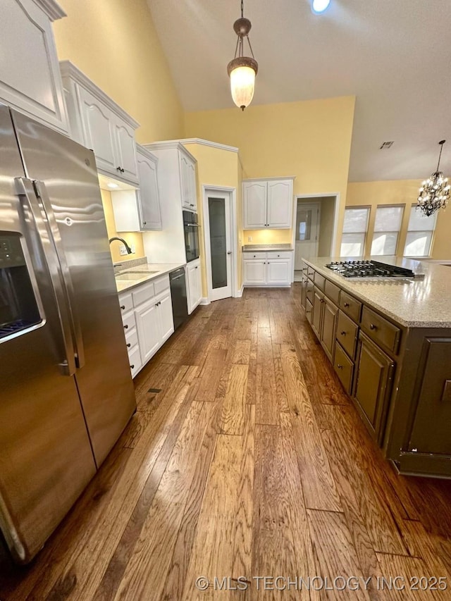 kitchen with sink, black appliances, decorative light fixtures, hardwood / wood-style flooring, and white cabinets